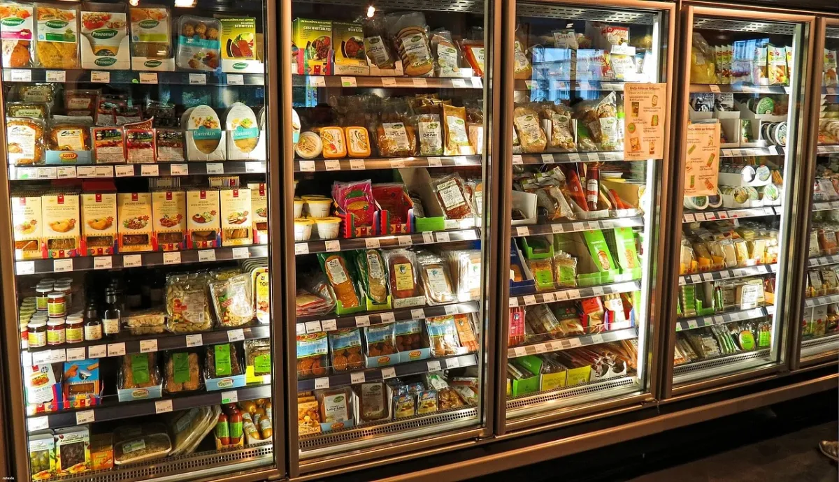Półki w lodówce supermarketu wypełnione świeżymi owocami i warzywami.
